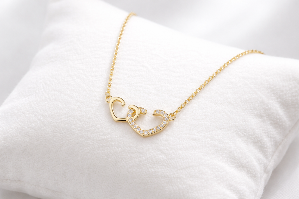 Gold necklace with heart and moon design on a white cushion