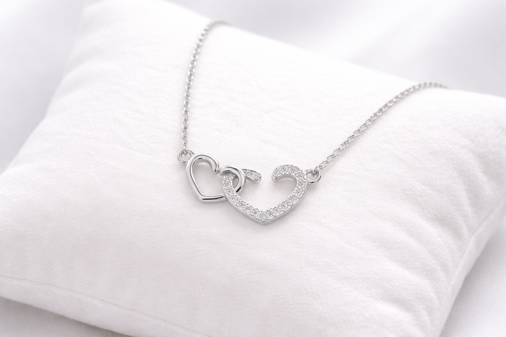 Silver necklace with heart-shaped pendant on a white cushion
