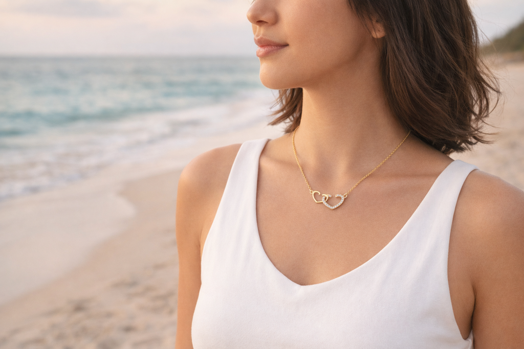 Woman wearing a gold necklace with a heart pendant on a beach