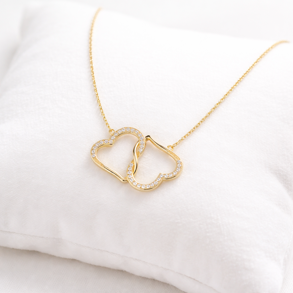 Gold necklace with interlocking heart pendants on a white background