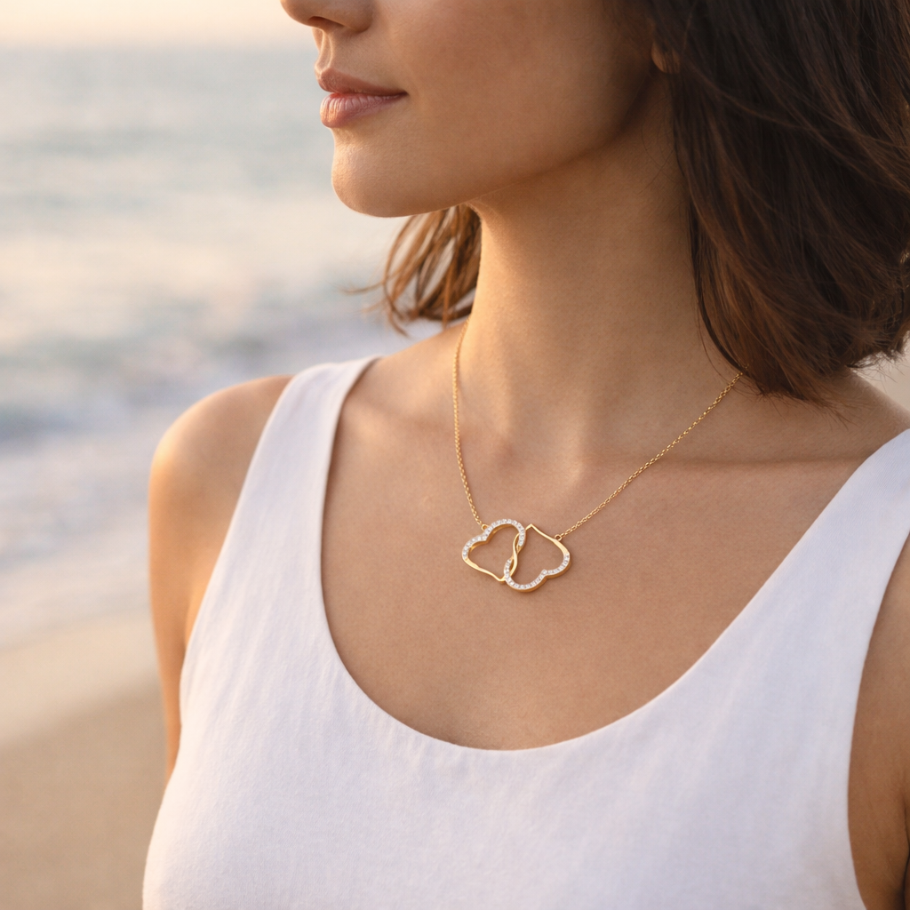 Woman wearing a gold necklace with a heart pendant on a beach.