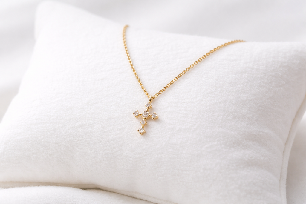Gold cross necklace on a white cushion