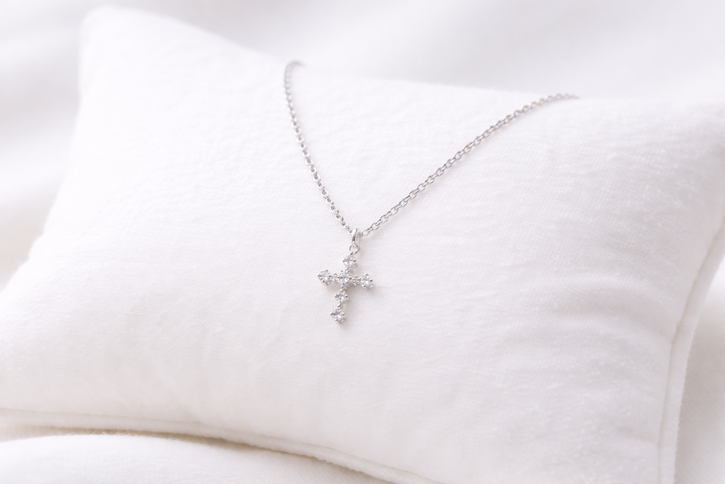 Silver cross necklace on a white cushion