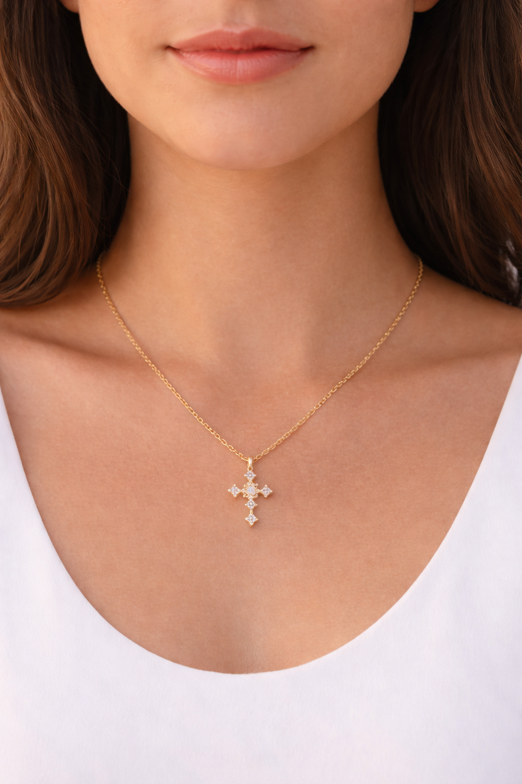 Gold necklace with a cross pendant worn by a person on a white background