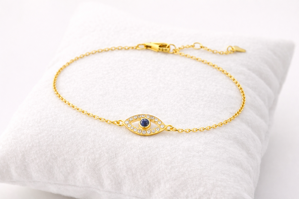Gold bracelet with a blue gemstone on a white cushion