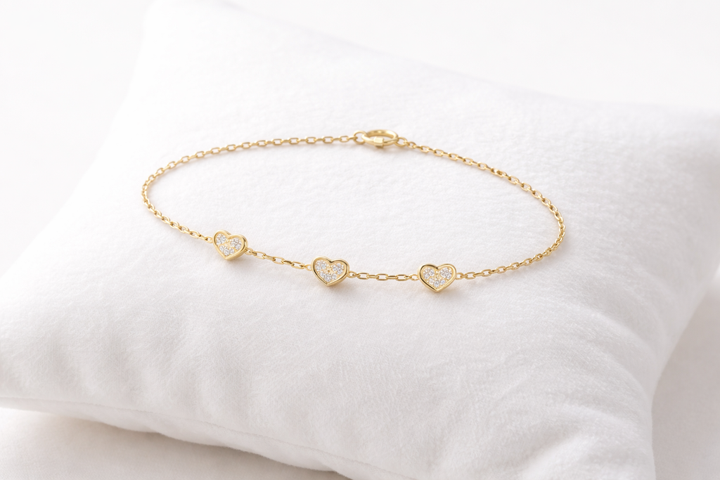 Gold bracelet with heart-shaped charms on a white cushion