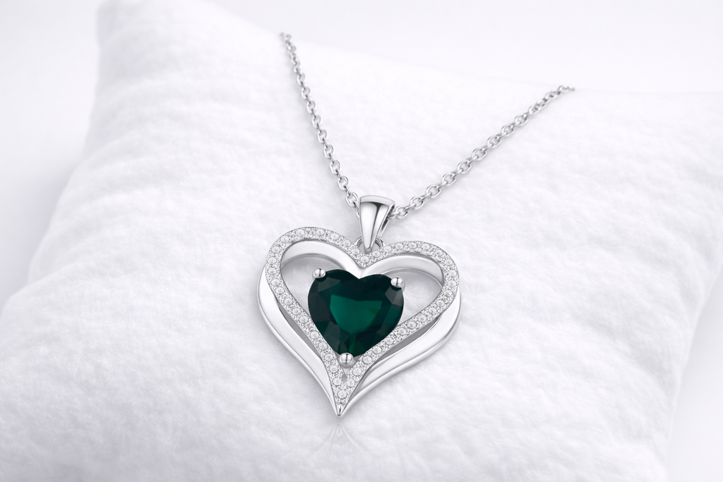 Heart-shaped pendant with a green gemstone on a white background