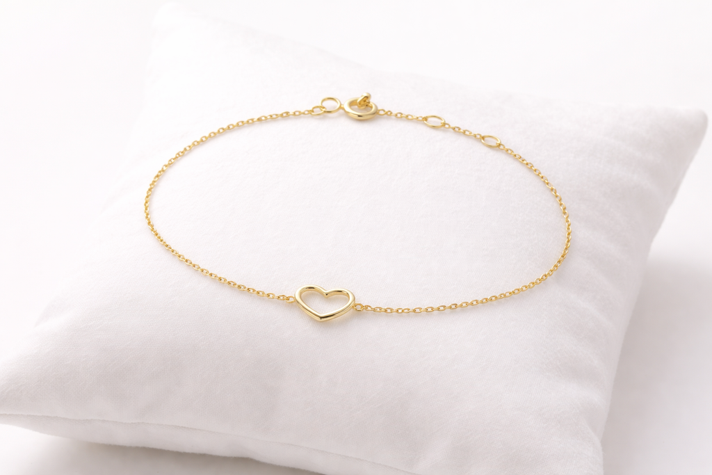 Gold bracelet with a heart charm on a white pillow