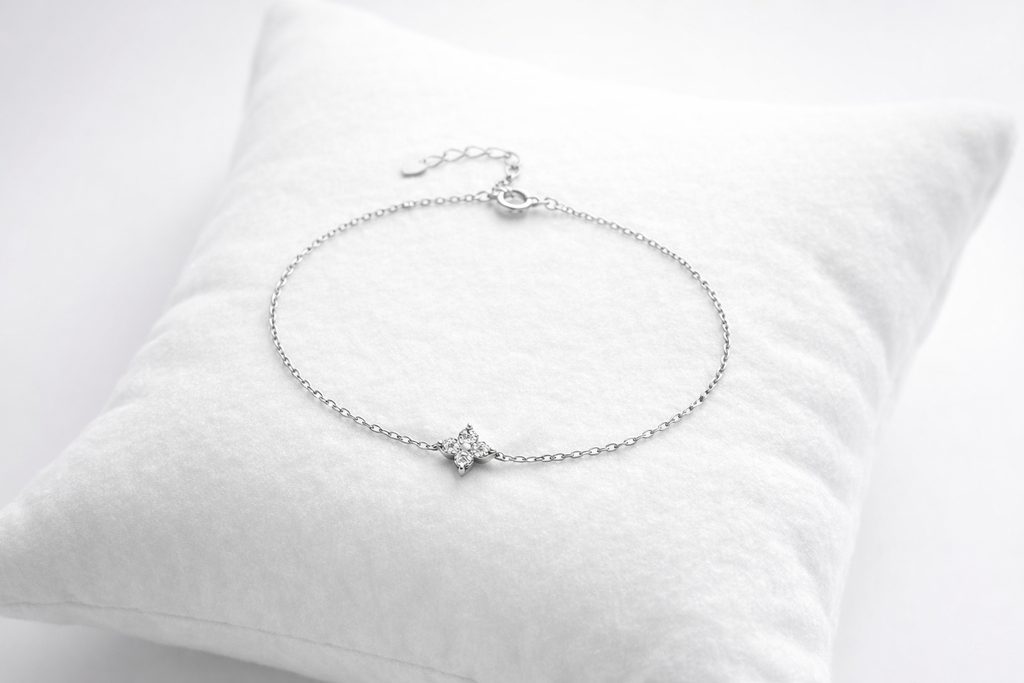Silver bracelet with a small heart charm on a white cushion