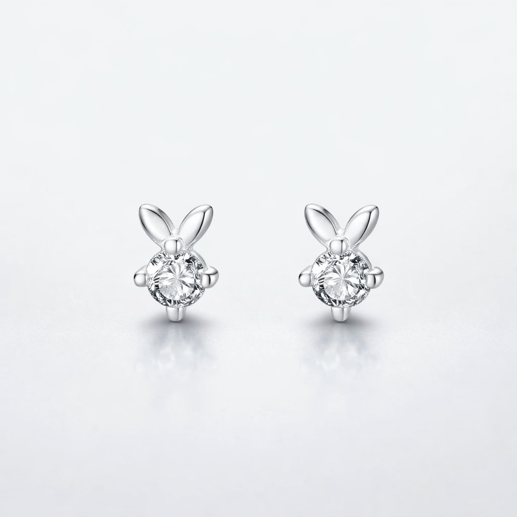 Pair of silver bunny-shaped earrings with clear gemstones on a light gray background