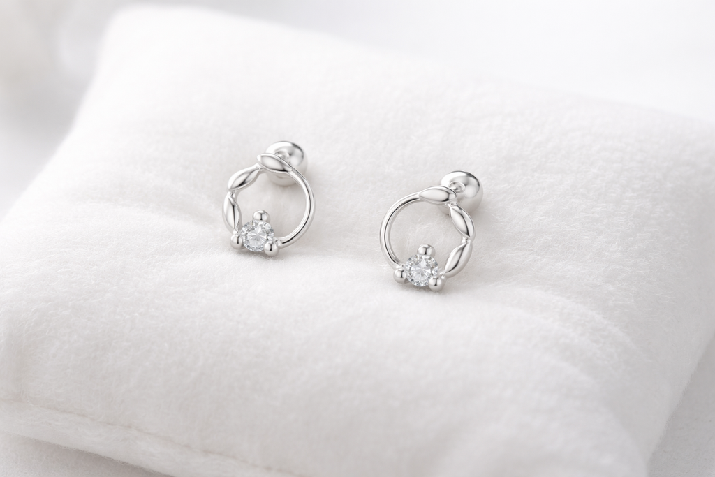 Pair of silver earrings with small diamonds on a white cushion