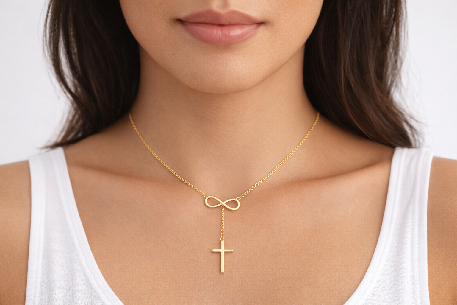 Gold necklace with an infinity symbol and cross pendant on a white background