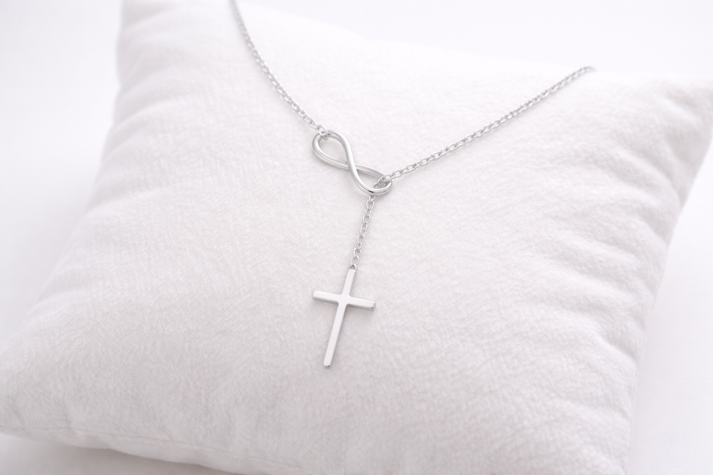 Silver cross necklace on a white pillow