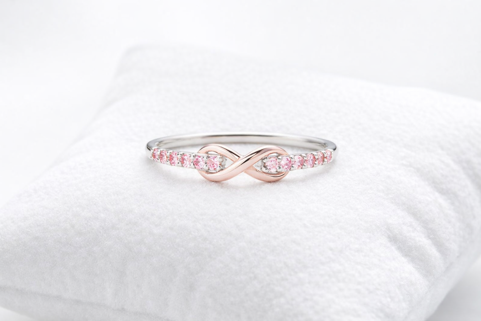 Rose gold ring with pink gemstones on a white background