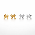 Pair of gold bow-shaped earrings and a pair of silver bow-shaped earrings on a white background.