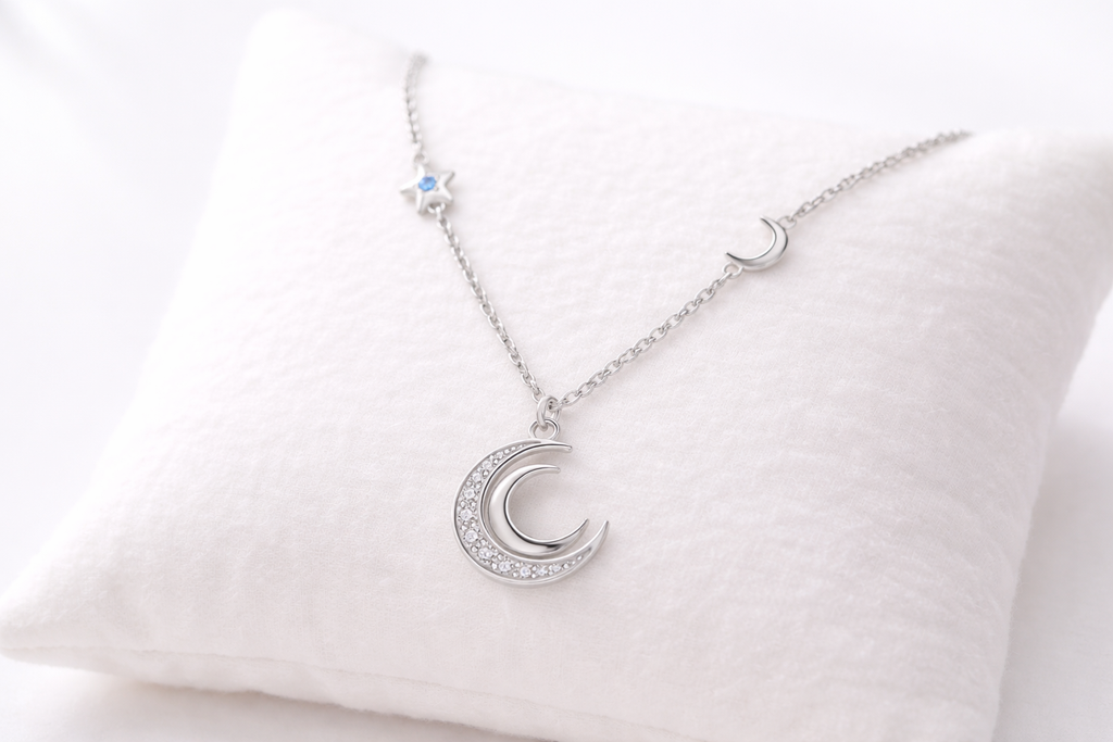 Silver necklace with a crescent moon pendant on a white cushion