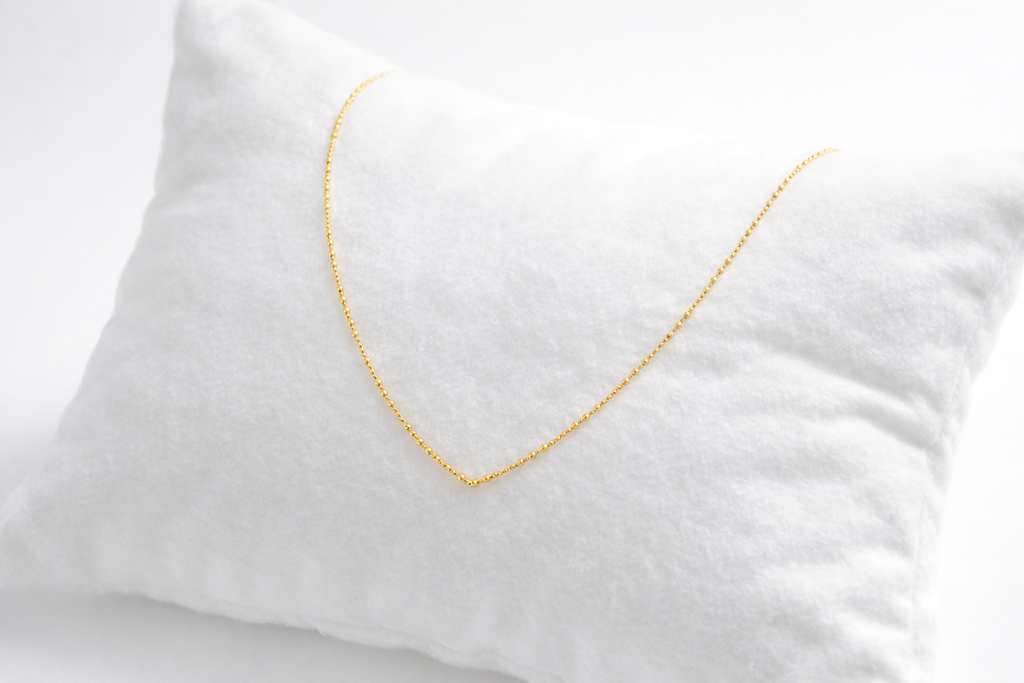 Gold necklace on a white pillow