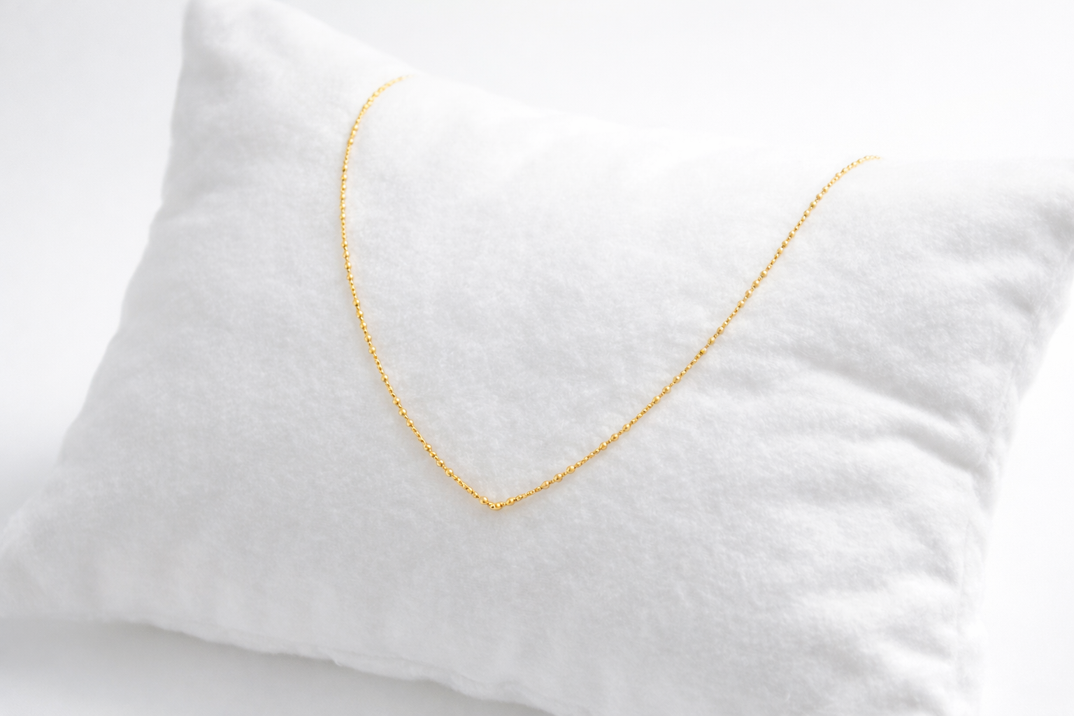 Gold necklace on a white pillow