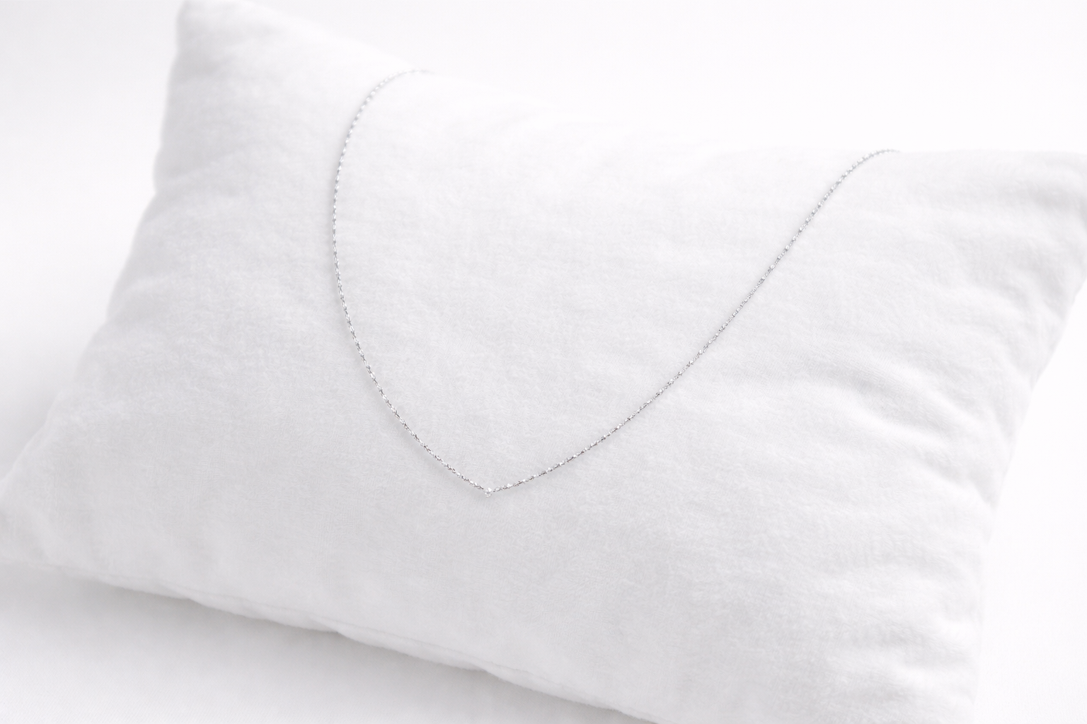 Close-up of a white pillow with a heart-shaped cutout on a light gray background