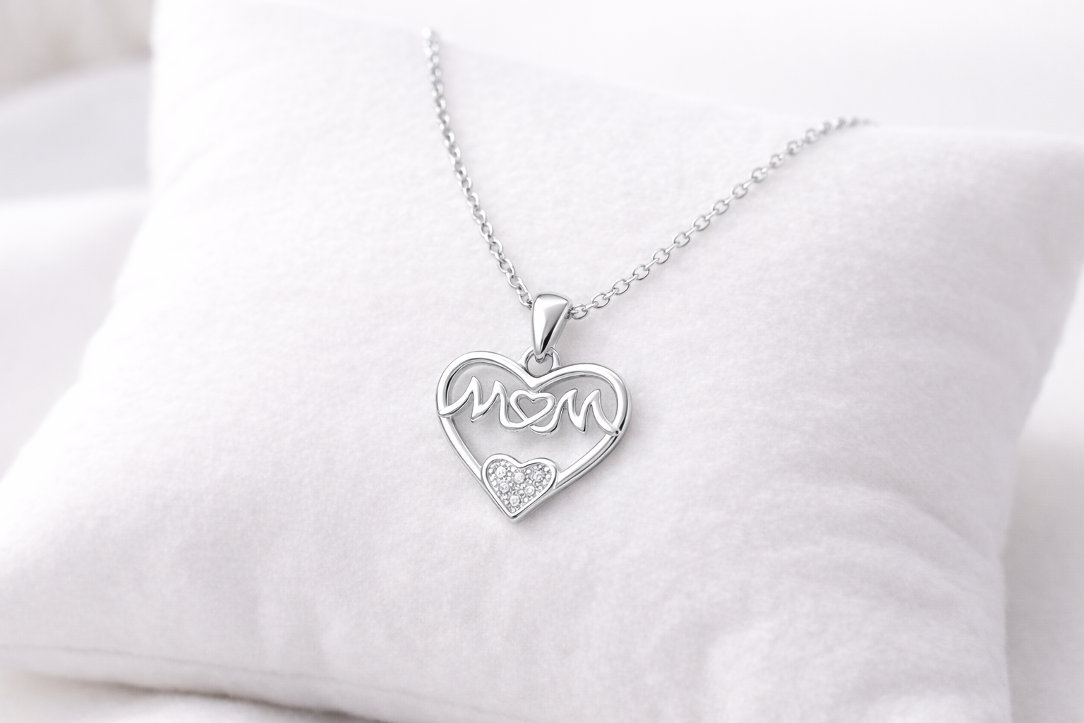 Silver necklace with a heart-shaped pendant on a white cushion