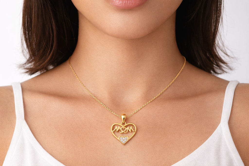 Gold necklace with a heart-shaped pendant on a person wearing a white top.