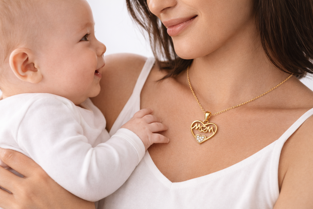 Woman holding a baby and wearing a gold necklace with a heart-shaped pendant