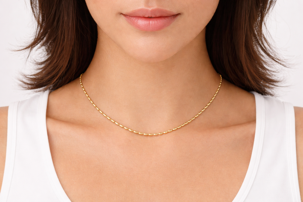 Gold necklace worn by a person with a white background
