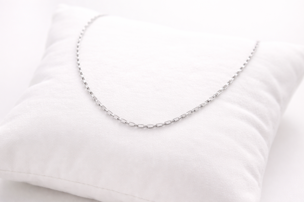 Silver chain necklace on a white pillow