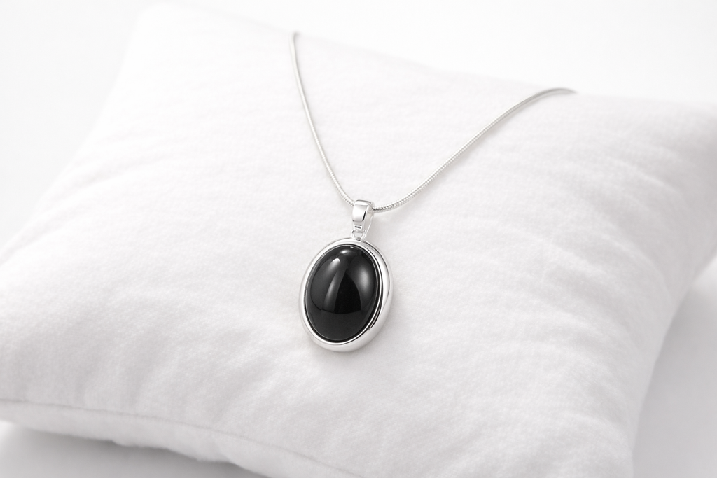 Black pendant necklace on a white pillow