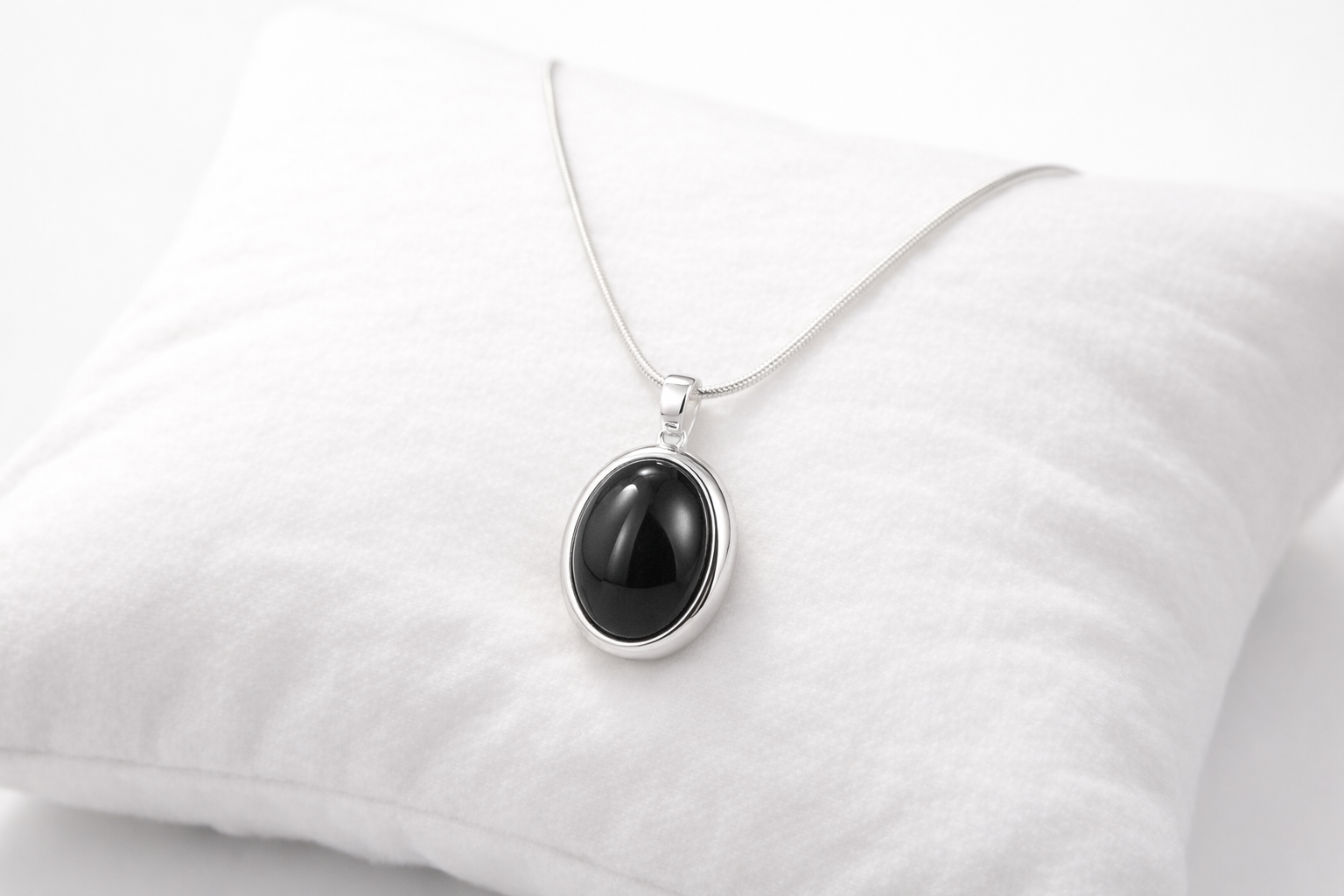 Black pendant necklace on a white pillow