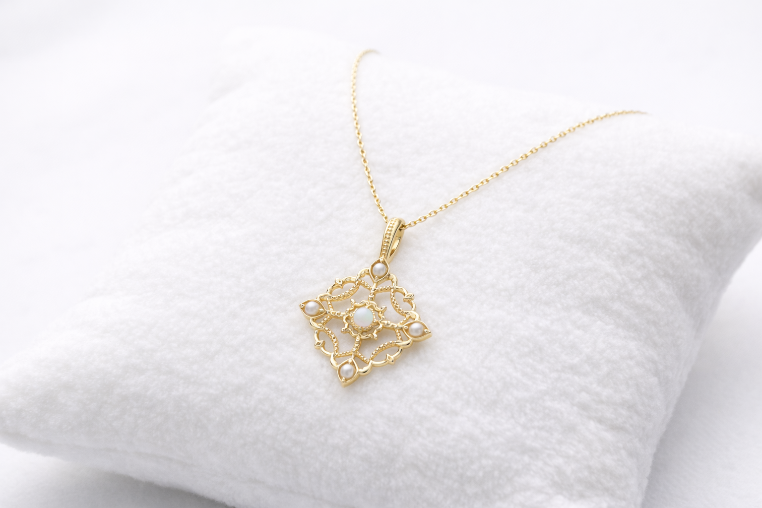 Gold necklace with a decorative pendant on a white cushion