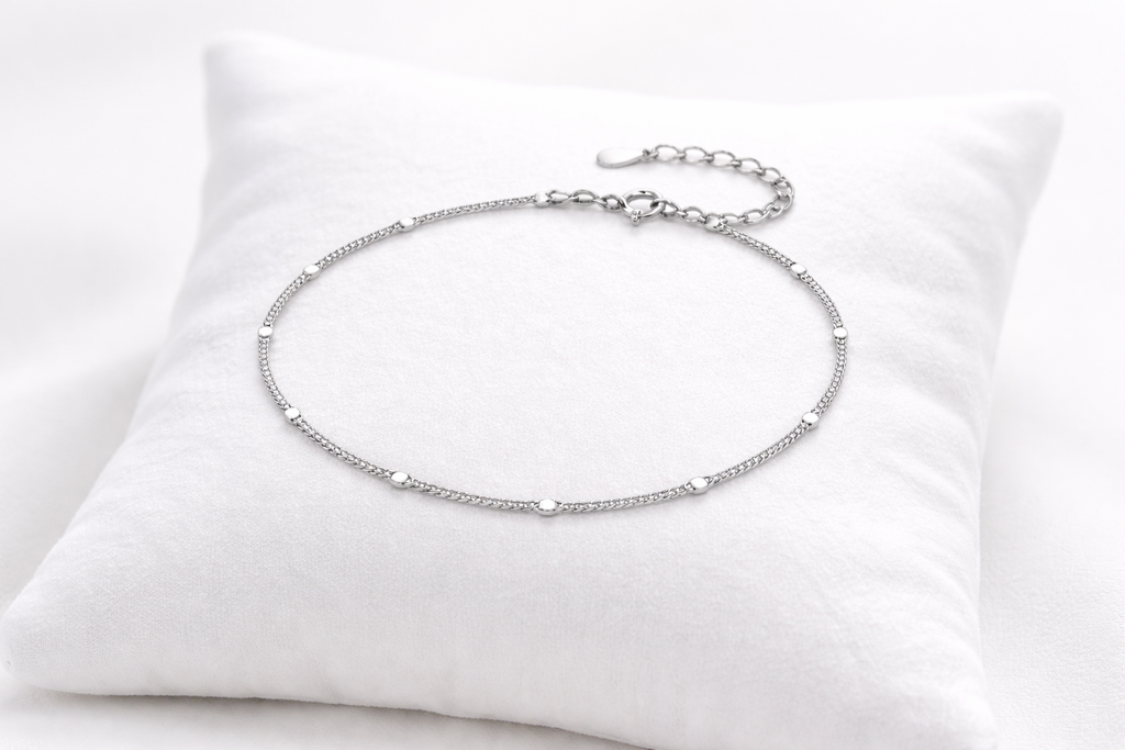 Silver anklet on a white pillow