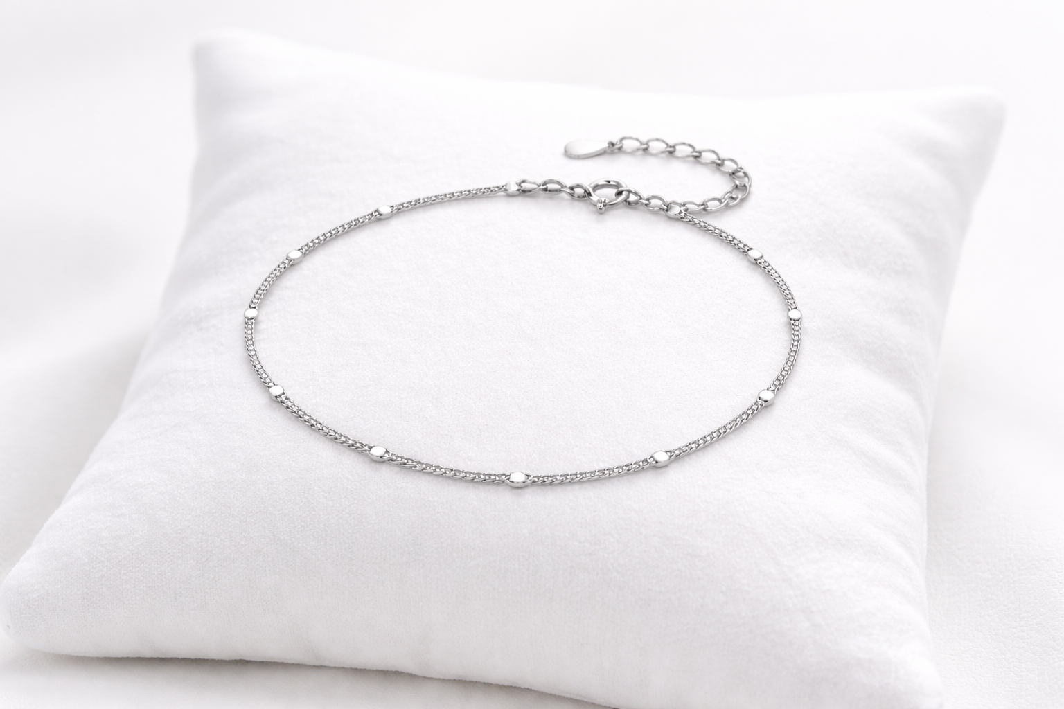 Silver anklet on a white pillow