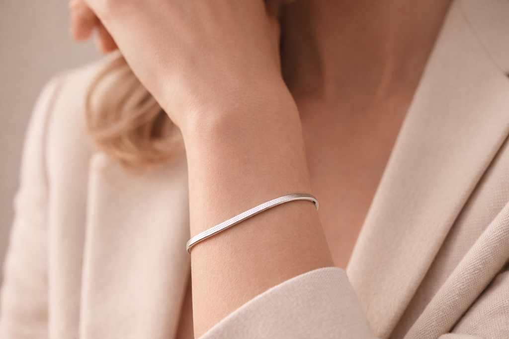 Silver bracelet on a person's wrist with a neutral background