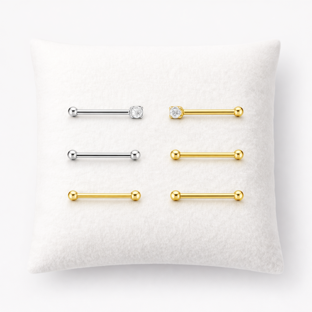 Set of gold and silver barbell earrings on a white pillow