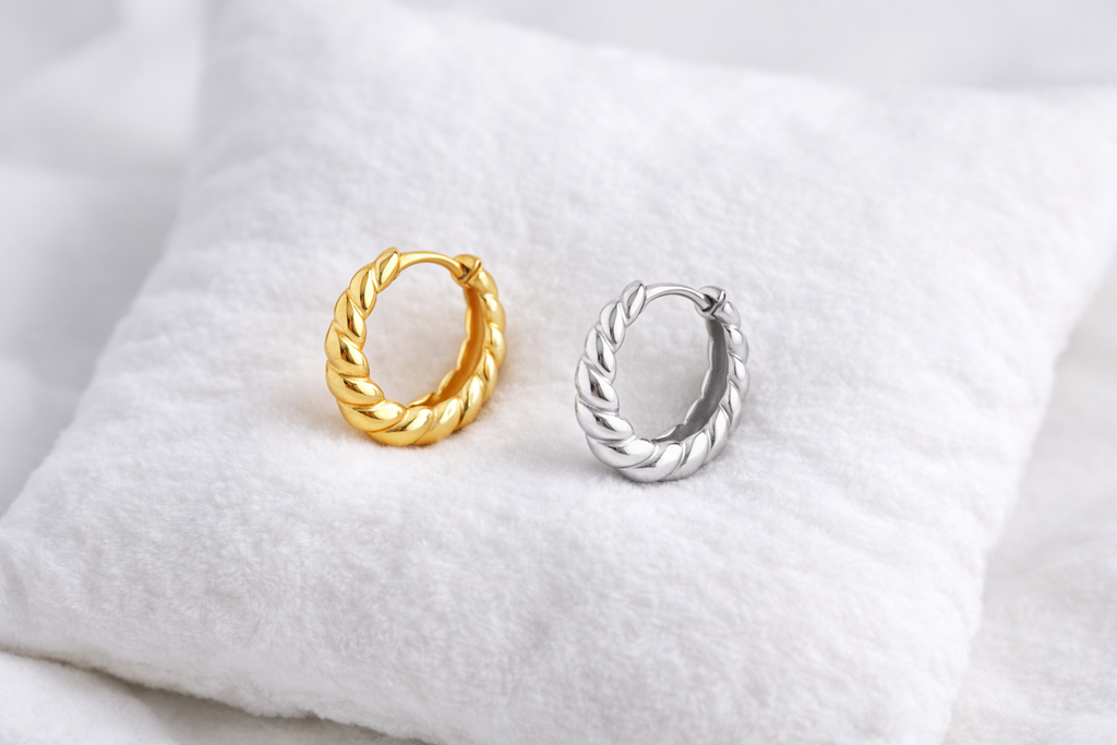 Gold and silver hoop earrings on a white fabric background