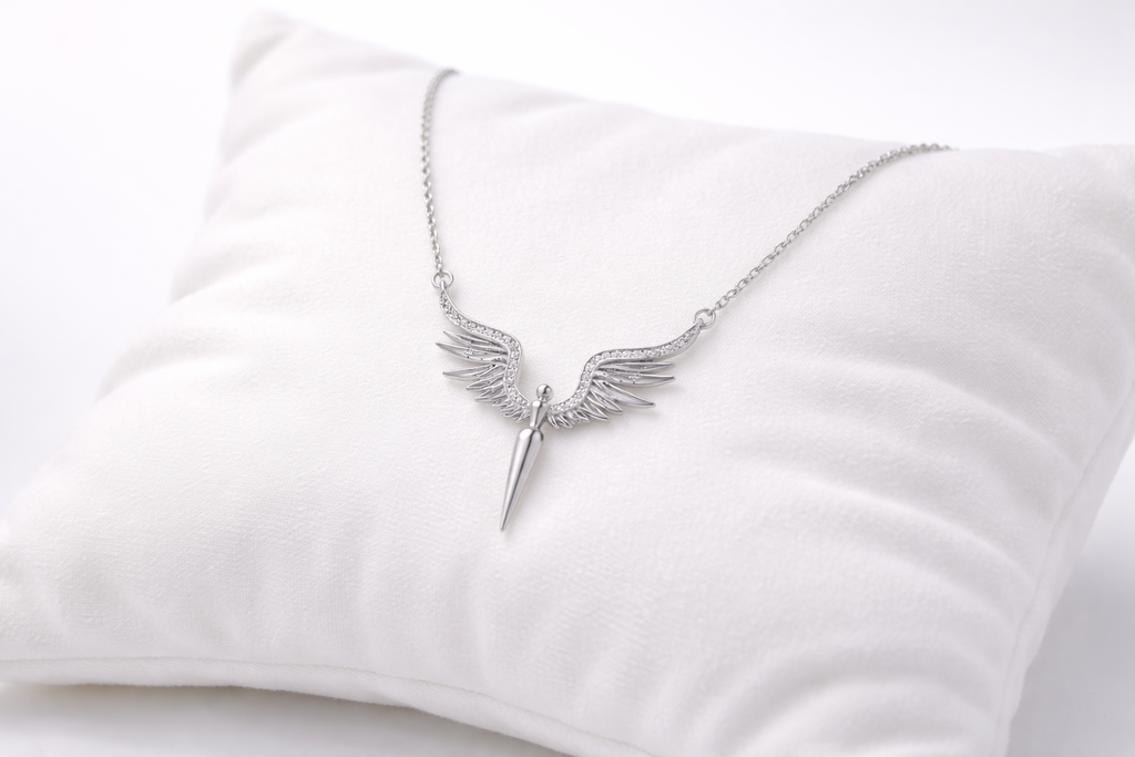 Silver winged necklace on a white cushion