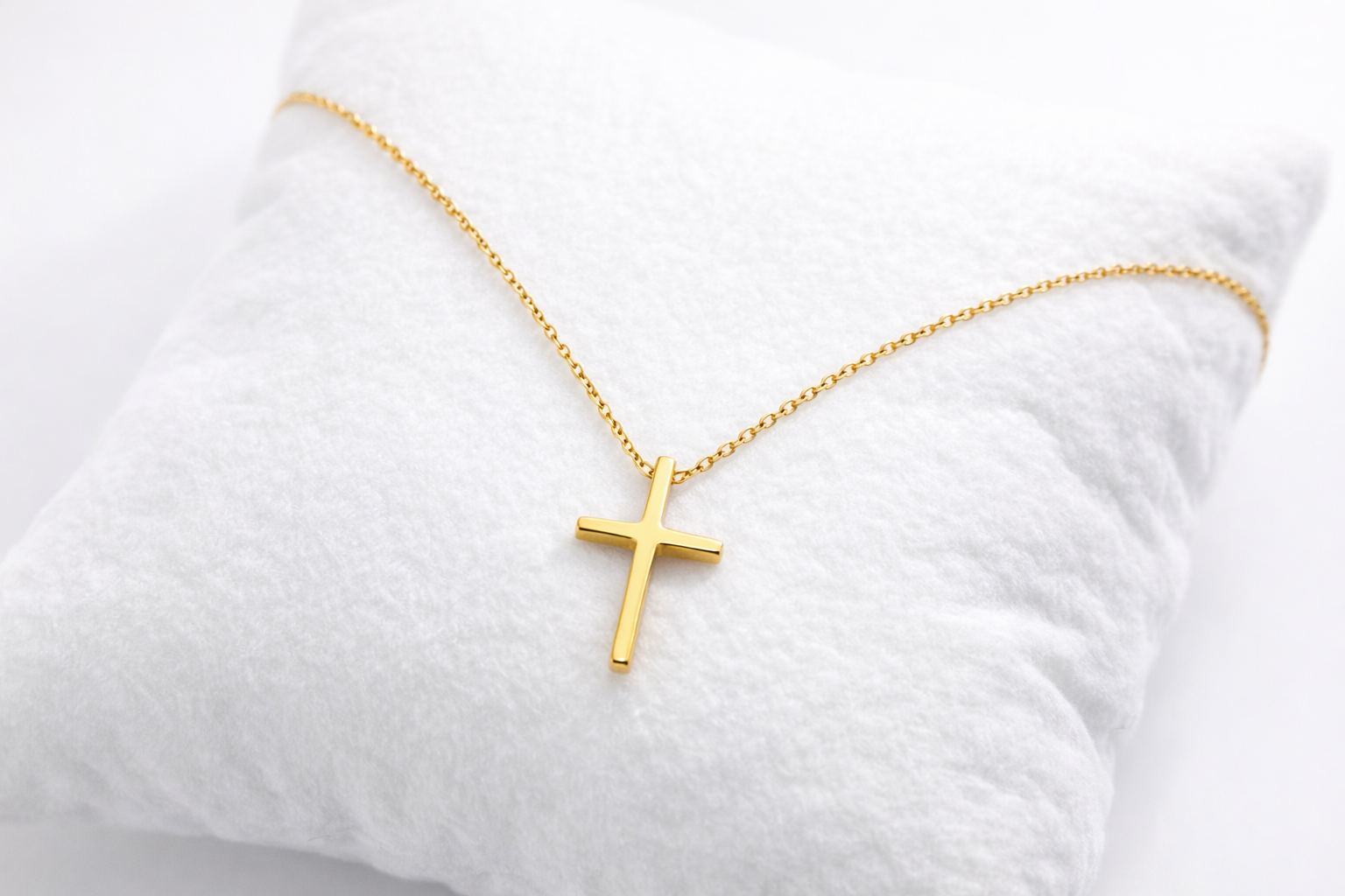 Gold cross necklace on a white pillow