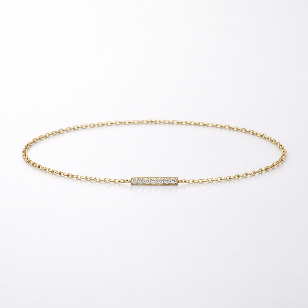 Gold bracelet with a small diamond bar on a light gray background