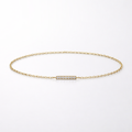 Gold bracelet with a small diamond bar on a light gray background