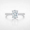 Diamond ring with a large central gemstone and smaller stones on a light gray background