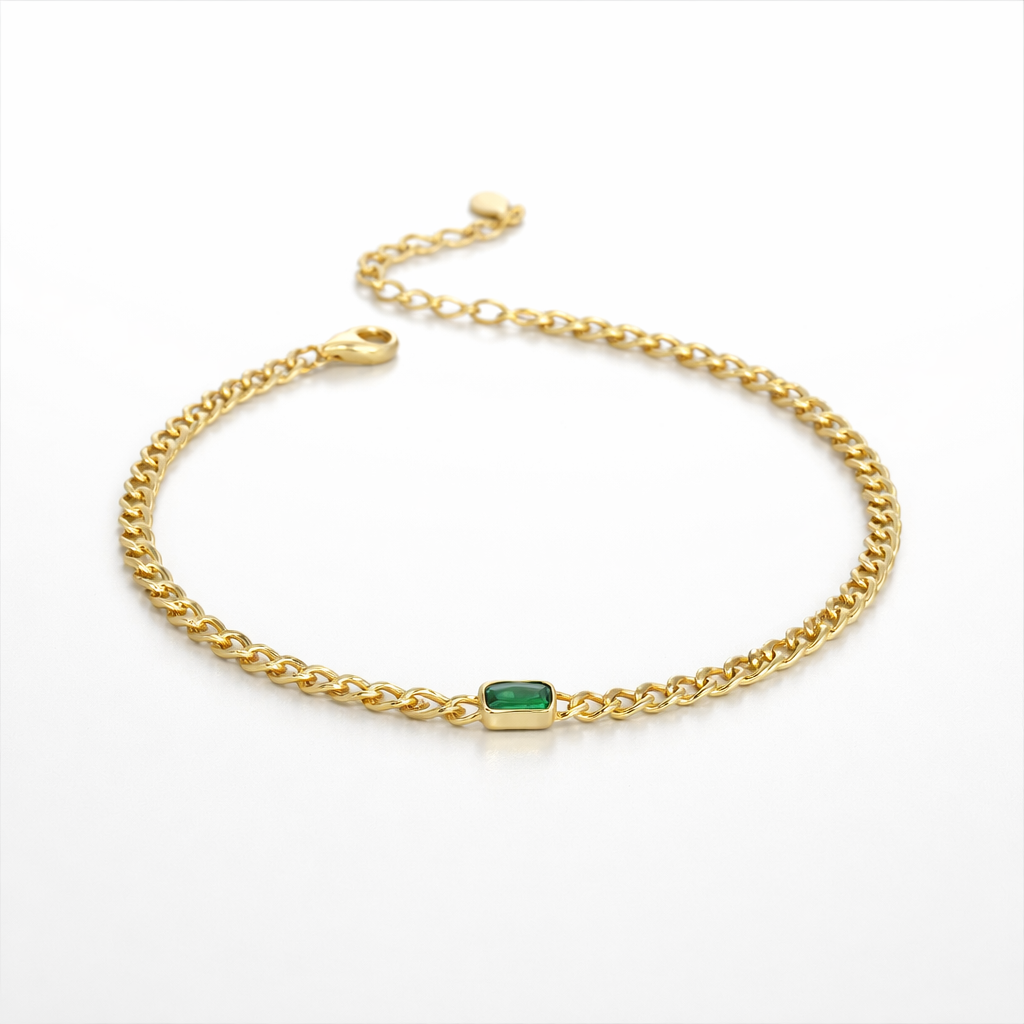 Gold chain bracelet with a green gemstone on a white background