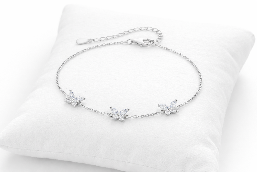 Silver bracelet with floral designs on a white cushion