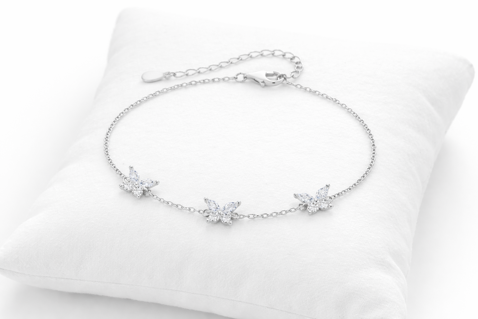Silver bracelet with floral designs on a white cushion
