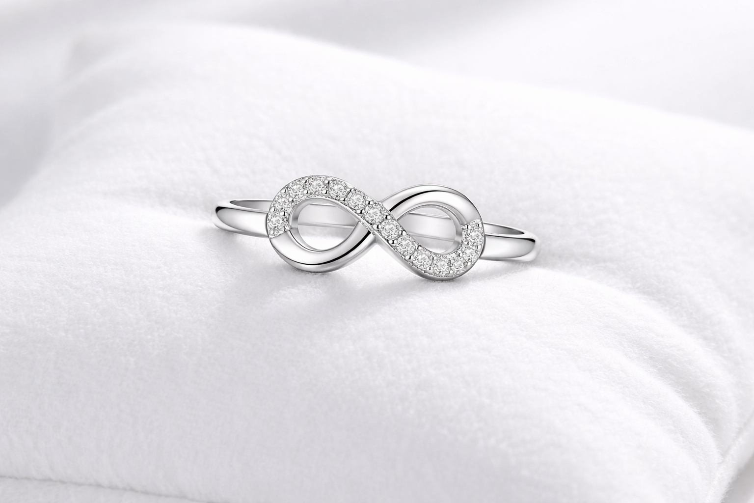 Silver infinity ring on a white satin background